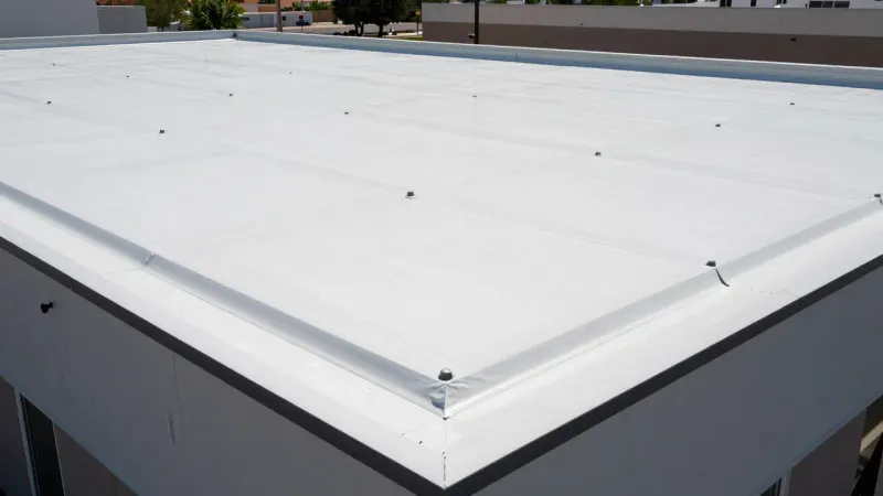 Completed TPO flat roof repair on a Lehi Utah commercial building showing clean membrane seams and drain area with natural daylight