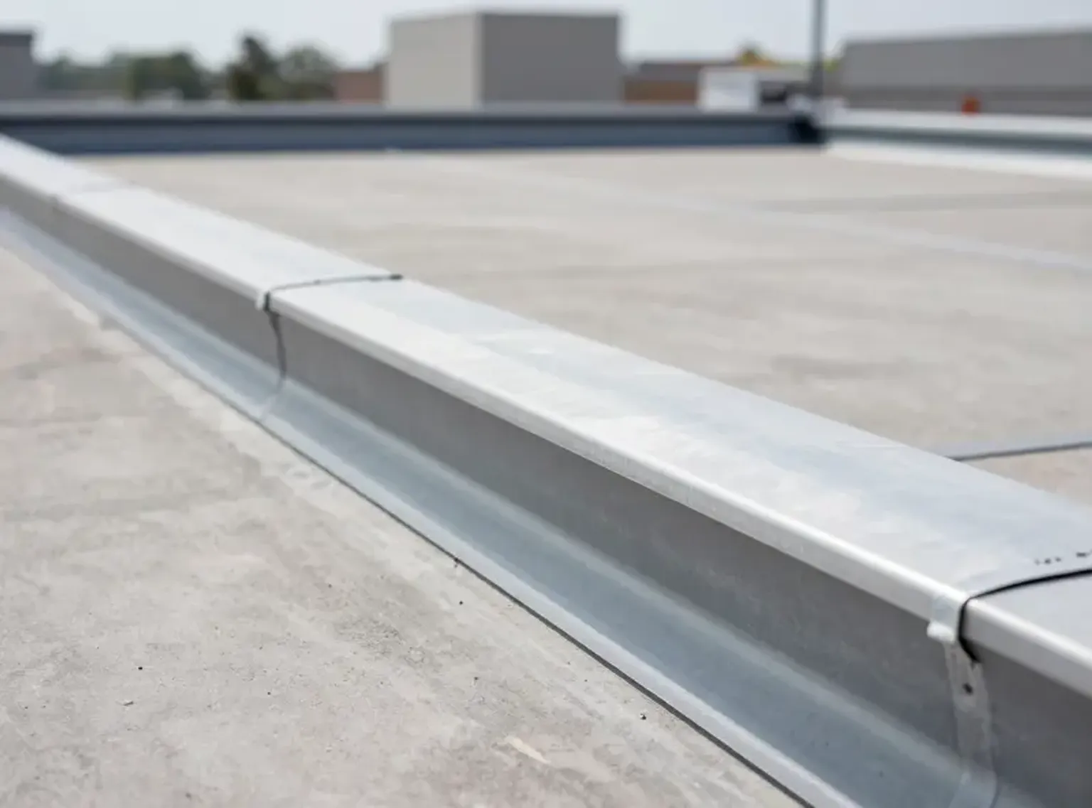 Documentary-style iPhone close-up of commercial roof drain and flashing detail on a Lehi Utah office building with natural daylight