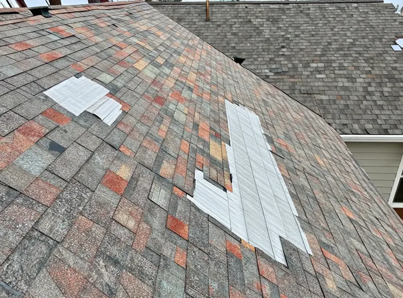 Documentary-style iPhone photo of completed temporary emergency repair on a Lehi Utah home securing the roof against further water damage