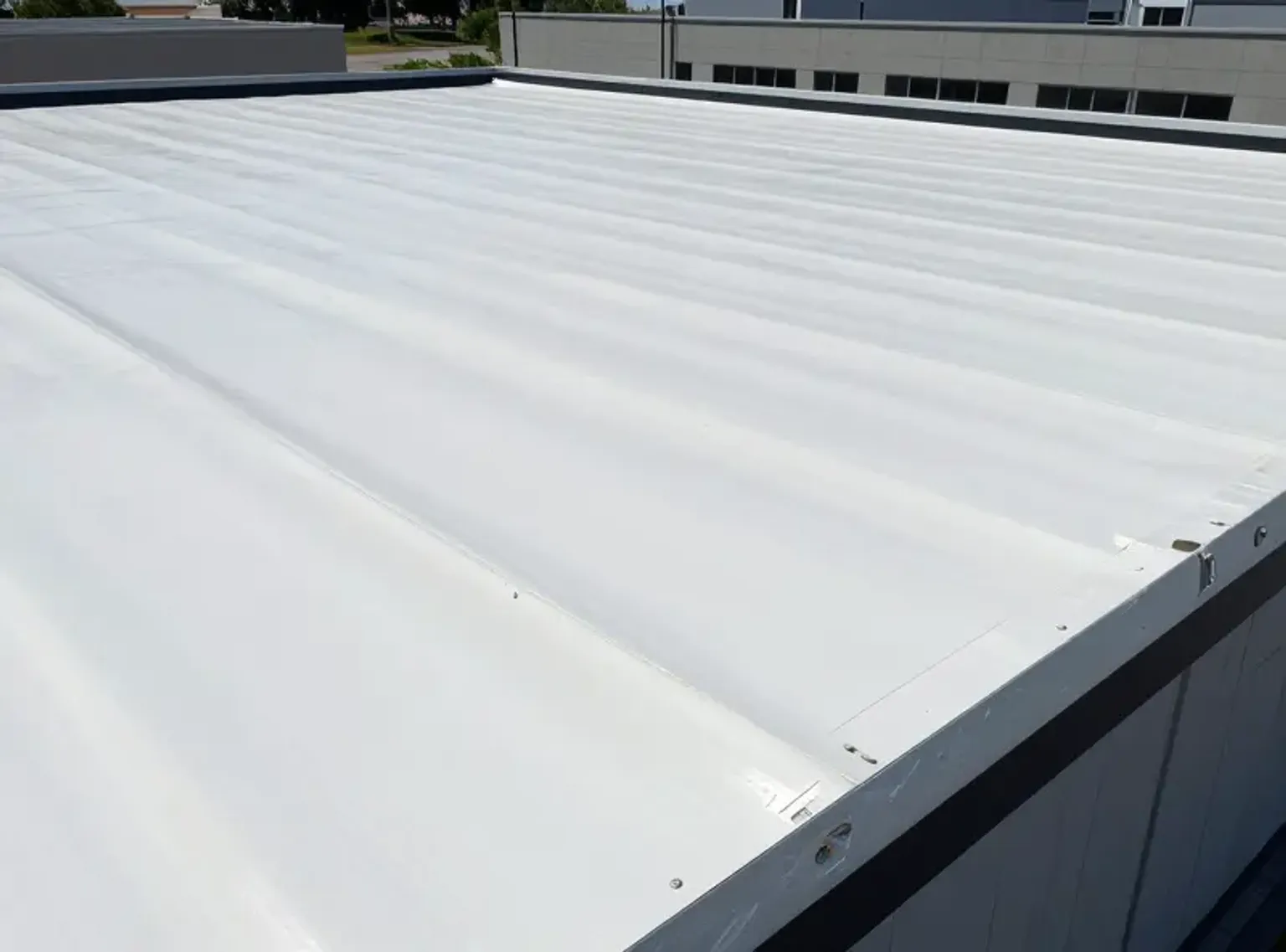 Documentary-style iPhone photo of TPO membrane seam repair in progress on a Lehi Utah flat roof commercial building with natural daylight