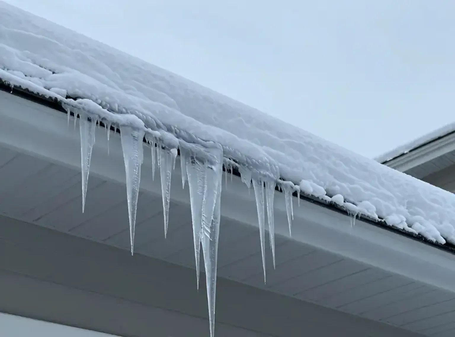 Documentary-style iPhone photo of commercial flat roof maintenance inspection showing drain clearing and membrane condition check on a Lehi Utah building